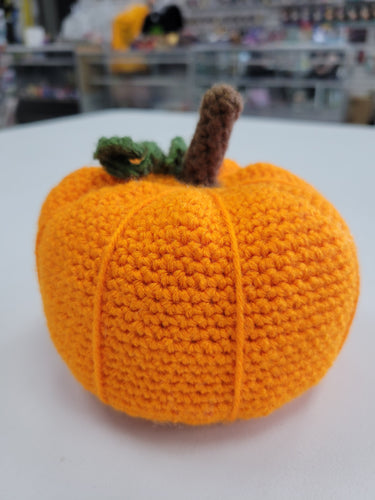 Orange crocheted pumpkin with a brown stem and green vine