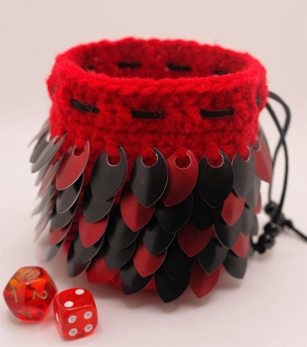 Dragon scale dice bag made from red yarn with red and black metallic scales.