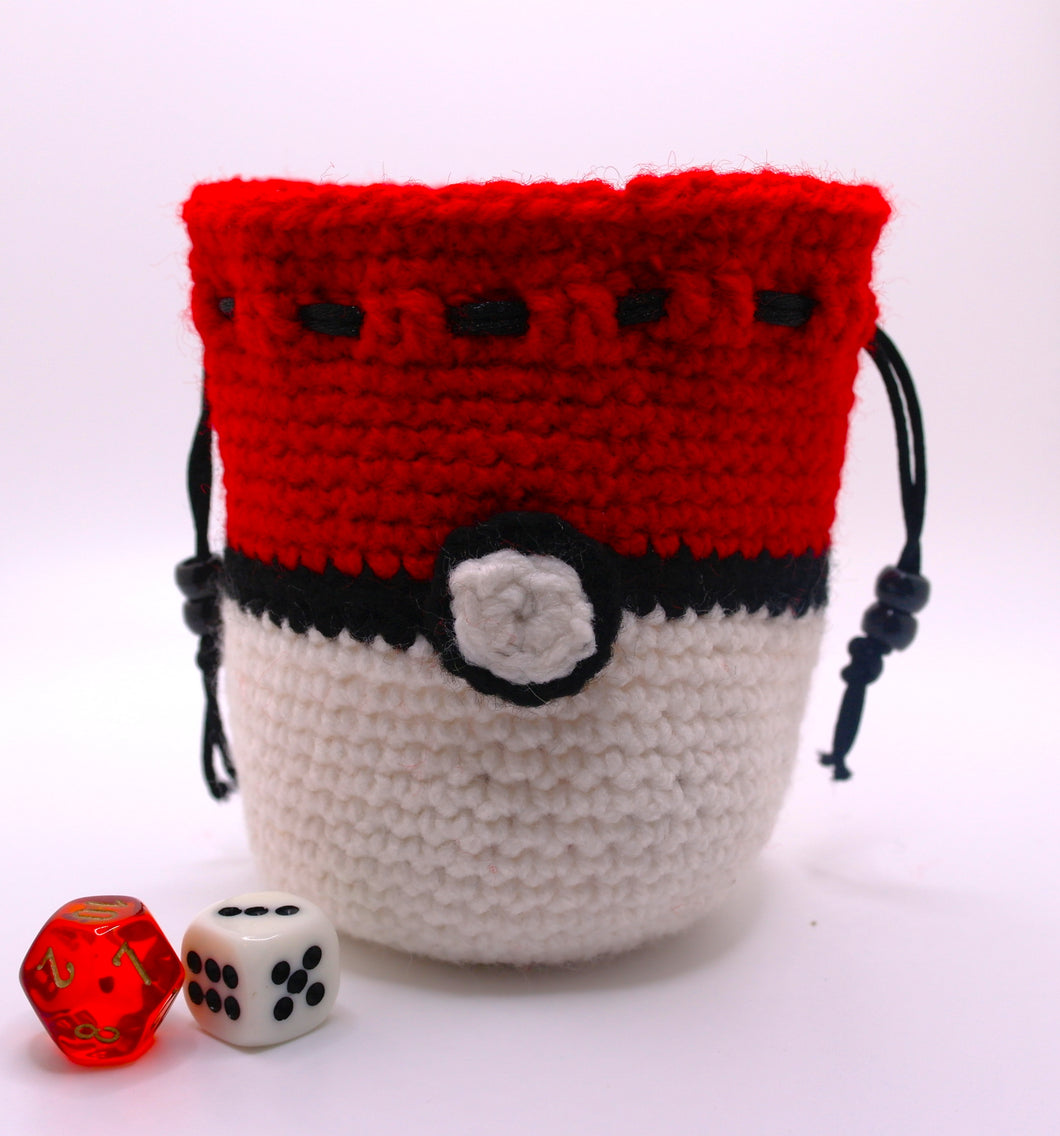Dice bag crocheted with white, black and red yarn to look like a pokeball with a black drawstring closure